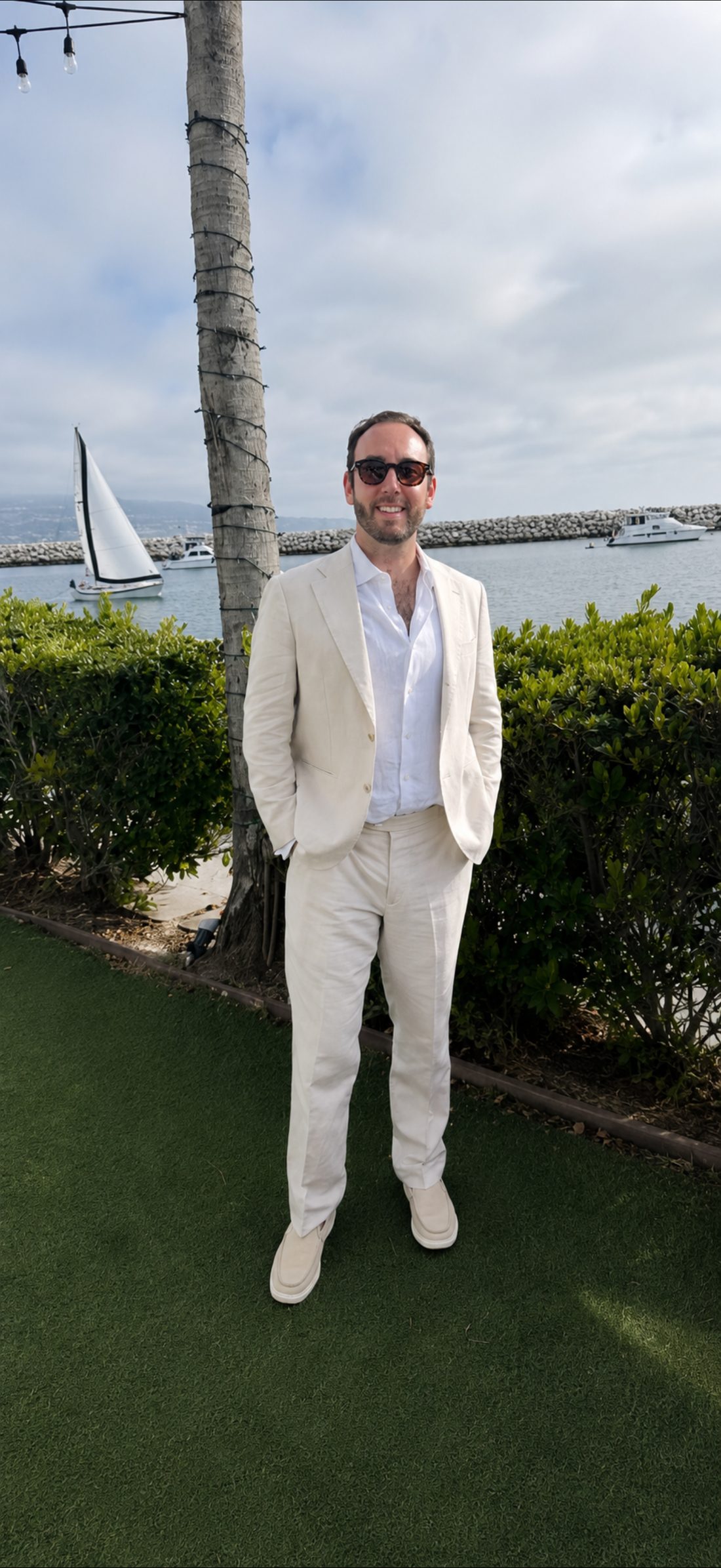 Alex Itkis in a cream linen suit at a marina in Southern California